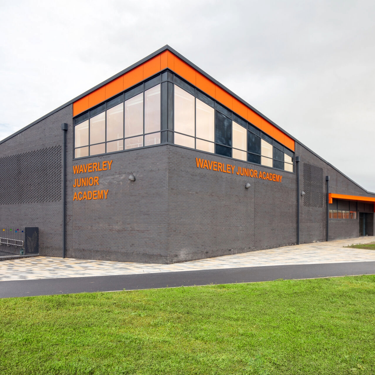 Waverley Junior Academy School in orange writing on the side of a grey brick building.